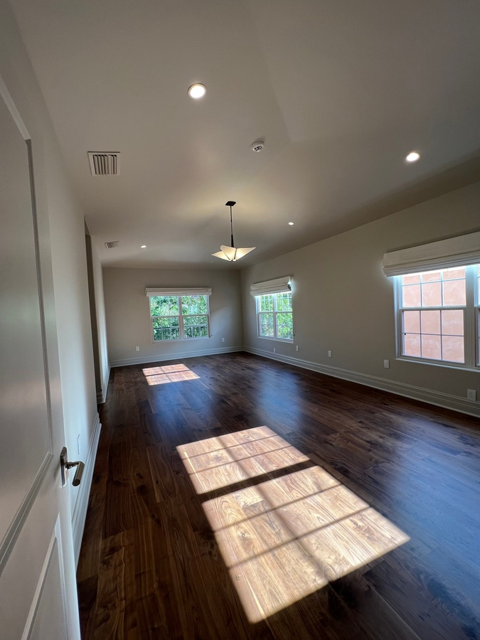 Renovated room with rich wood flooring and recessed lighting by Wade Caldwell Construc