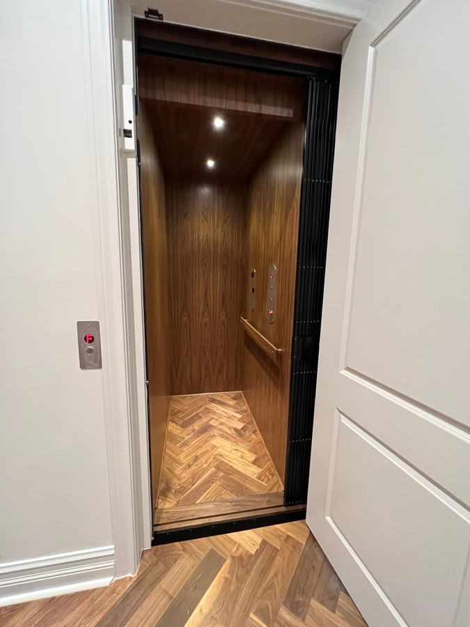 Residential elevator with wood interior and herringbone floor installed by Wade Caldwe