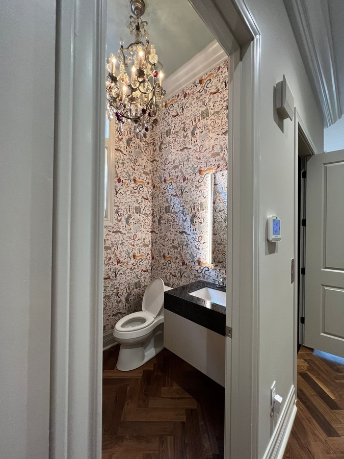 Wade Caldwell Construction bathroom remodel with unique wallpaper and elegant light fi