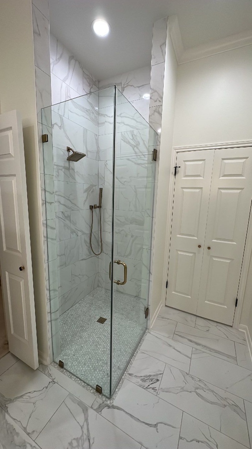 Frameless glass shower with marble tile in remodeled Alamo Heights bathroom by Wade Caldwe