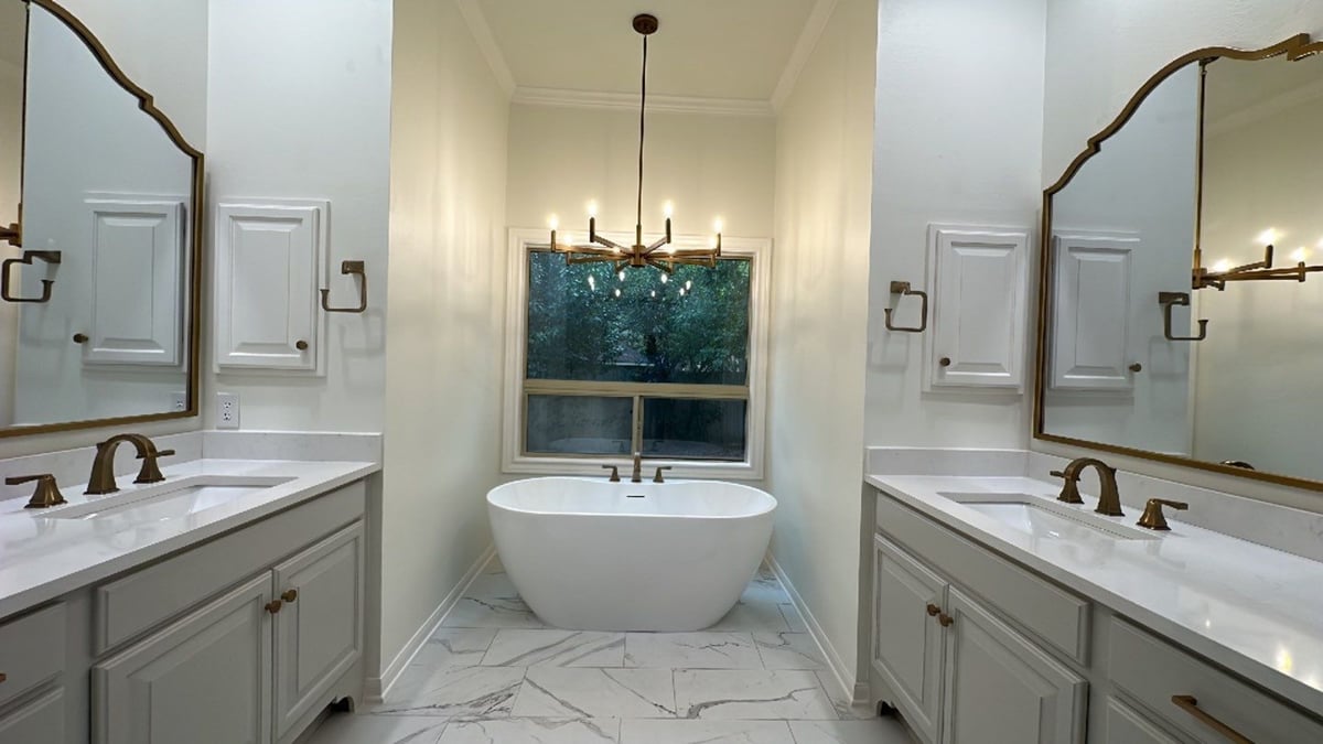 Remodeled Alamo Heights bathroom with double vanities and freestanding tub by Wade Caldwel