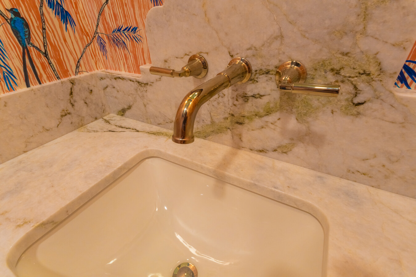 Luxury bathroom vanity with marble backsplash and brass faucet in Olmos Park, TX by Wade Caldwell 