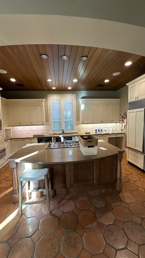 Central kitchen island with cooktop and wood cabinetry in Terrell Hills, TX remodel by Wade Caldw