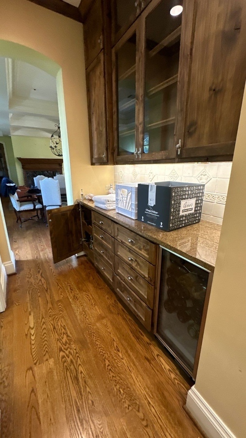 Custom dry bar remodel with glass-front cabinets and wine fridge in Terrell Hills, TX by Wade Cal