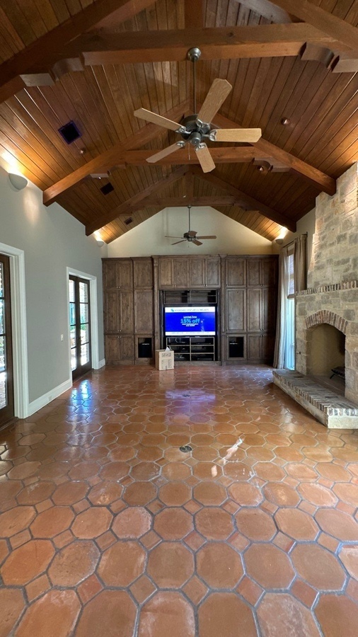 Living room remodel with exposed beams, media center, and stone fireplace in Alamo Heights, TX by