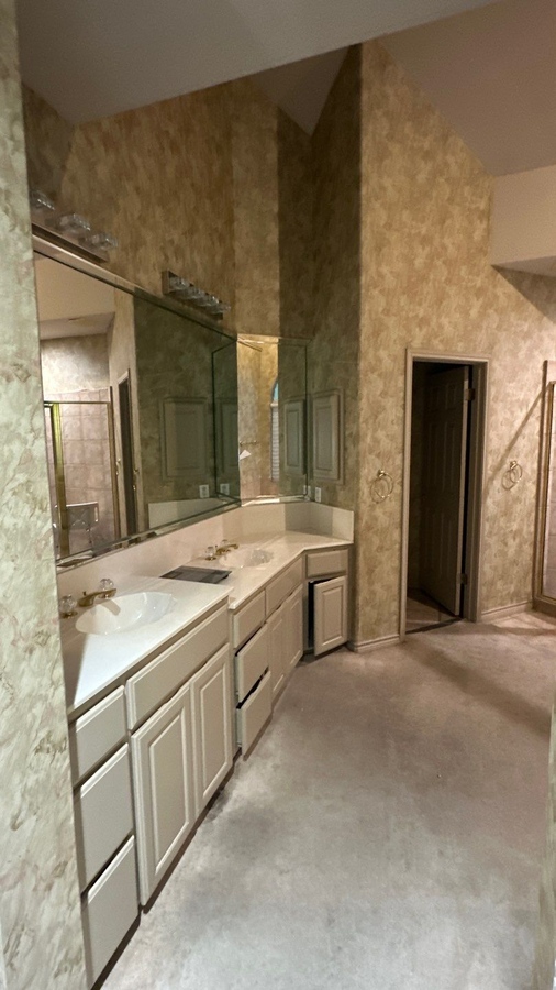 Pre-remodel master bathroom with dual sinks and wraparound mirrors captured