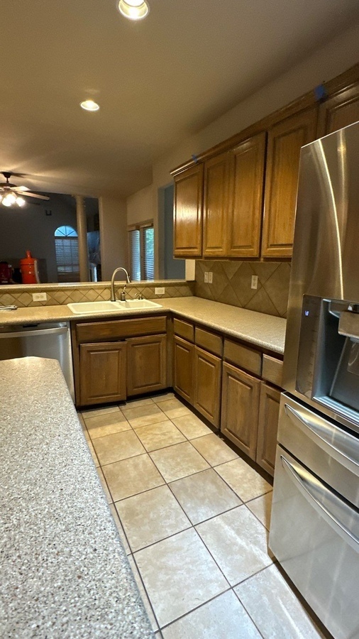 U-shaped kitchen with tile floor, dated cabinets, and laminate countertops 