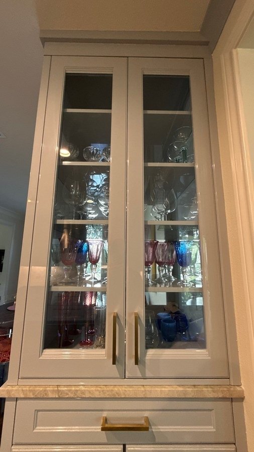 Glass-front display cabinets showcasing colorful glassware in San Antonio kitchen remodel by Wa