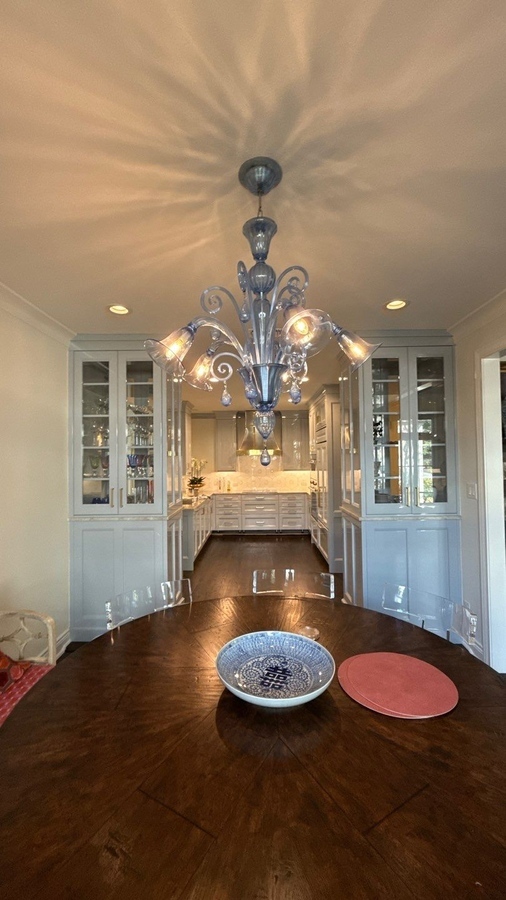 View into custom kitchen from formal dining area with chandelier in San Antonio remodel by Wade