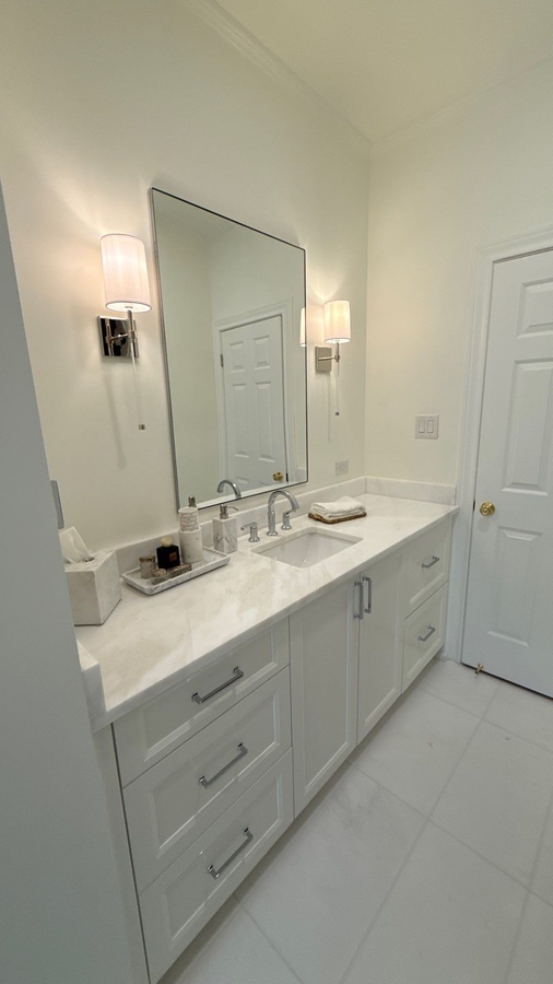 Clean white bathroom renovation featuring custom drawers and updated lighting by Wade C