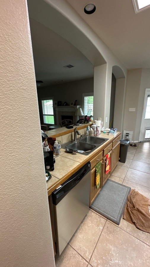 Dated kitchen setup with tiled backsplash and dual-basin sink in San Antonio by Wade Caldwell Constr