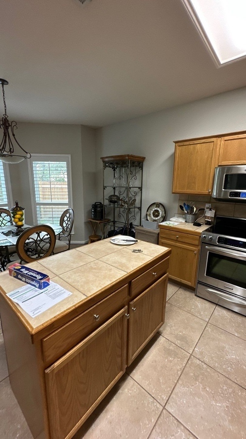 Existing kitchen layout with natural wood cabinets and tile surface island in San Antonio by Wade Ca
