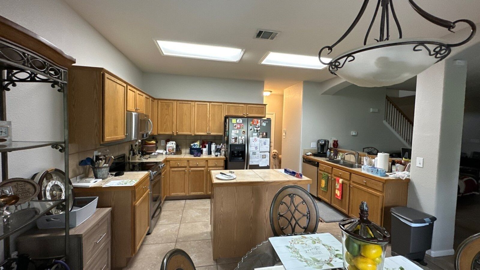View of kitchen and dining room with outdated lighting and cabinetry before remodel by Wade Caldwell