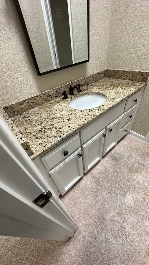 Compact bathroom vanity with granite top and updated hardware in Castle Hills, TX by Wade Cald
