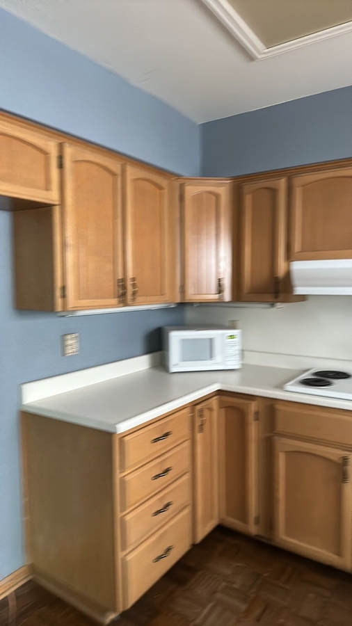 L-shaped kitchen corner with wood cabinets and laminate countertops before remodel by Wade Cal