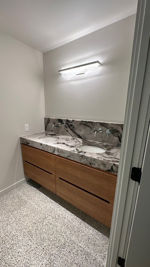 Double vanity with dramatic marble countertop and wood base in San Antonio, TX by Wade
