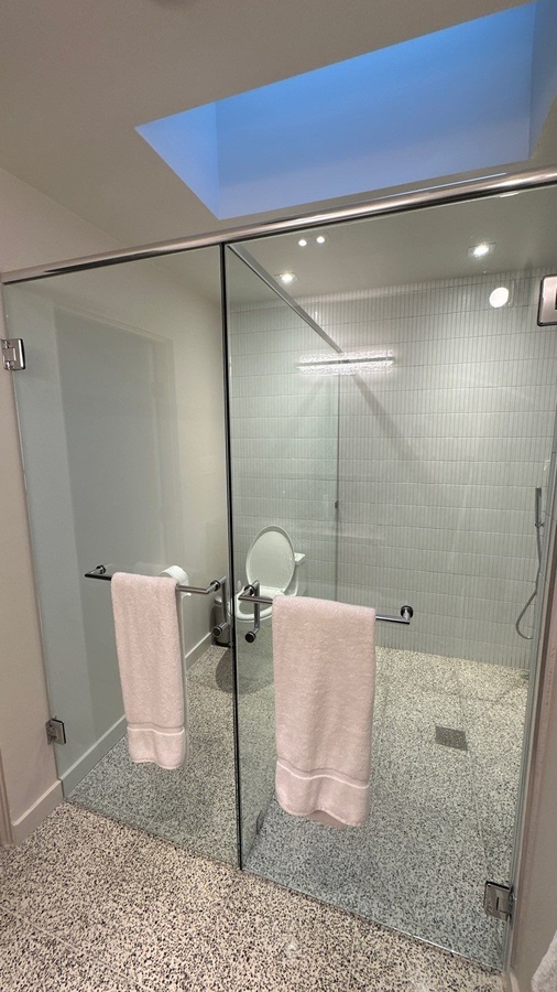 Modern walk-in shower with glass doors and skylight by Wade Caldwell Construction in S