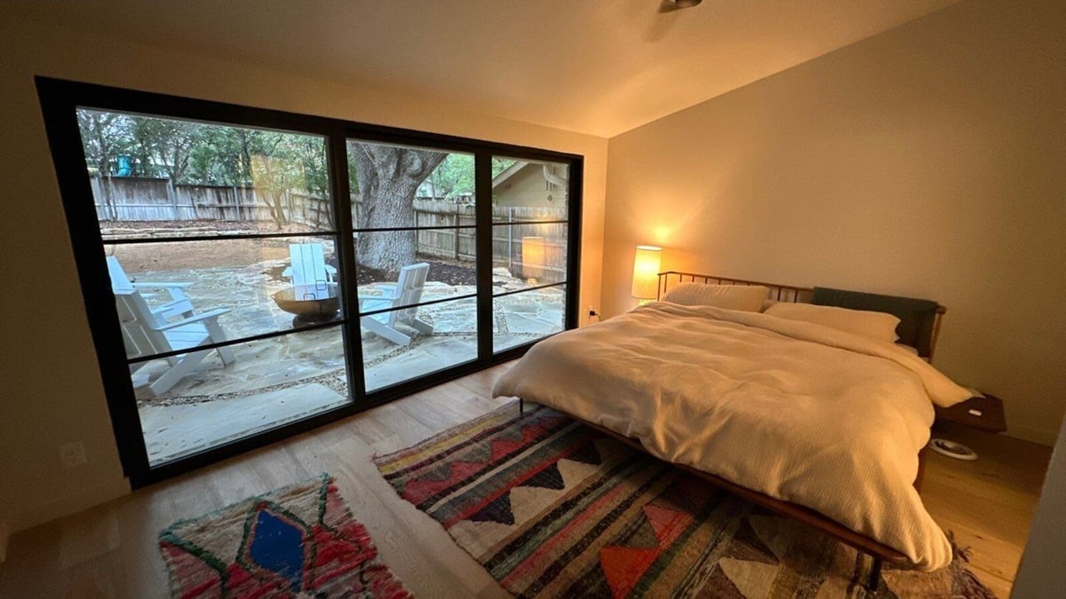Peaceful bedroom with modern furnishings and sliding glass doors leading to stone pati