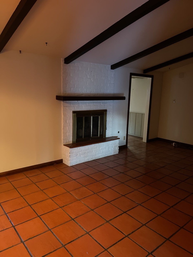 Dated living room space with terracotta tile floors in San Antonio undergoing remodel