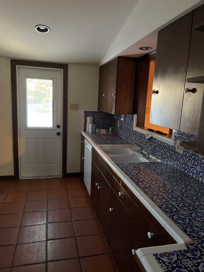 Pre-renovation galley kitchen with blue tiled counters in San Antonio by Wade Caldwel